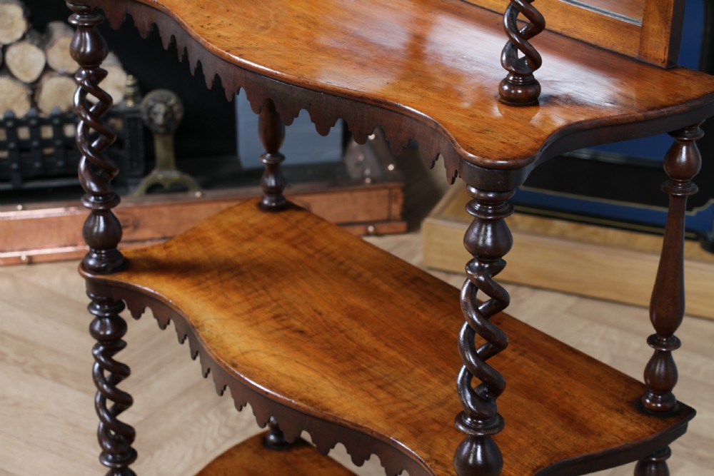 A Victorian six-tier walnut whatnot display shelf featuring hollow barley twist columns, mirrored back panels, and carved fretwork cresting. View XIX