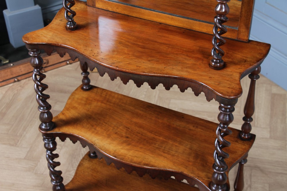 A Victorian six-tier walnut whatnot display shelf featuring hollow barley twist columns, mirrored back panels, and carved fretwork cresting. View XX