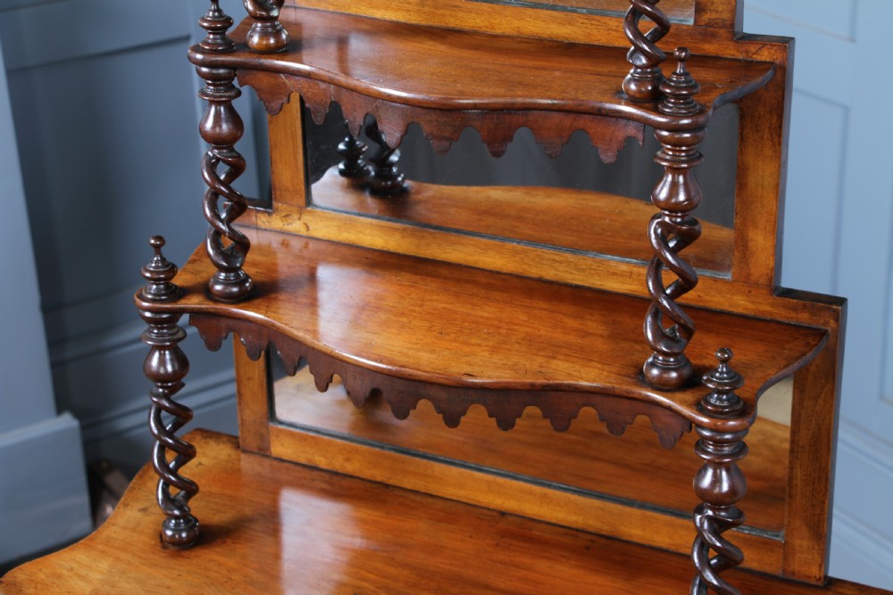 A Victorian six-tier walnut whatnot display shelf featuring hollow barley twist columns, mirrored back panels, and carved fretwork cresting. View XXI