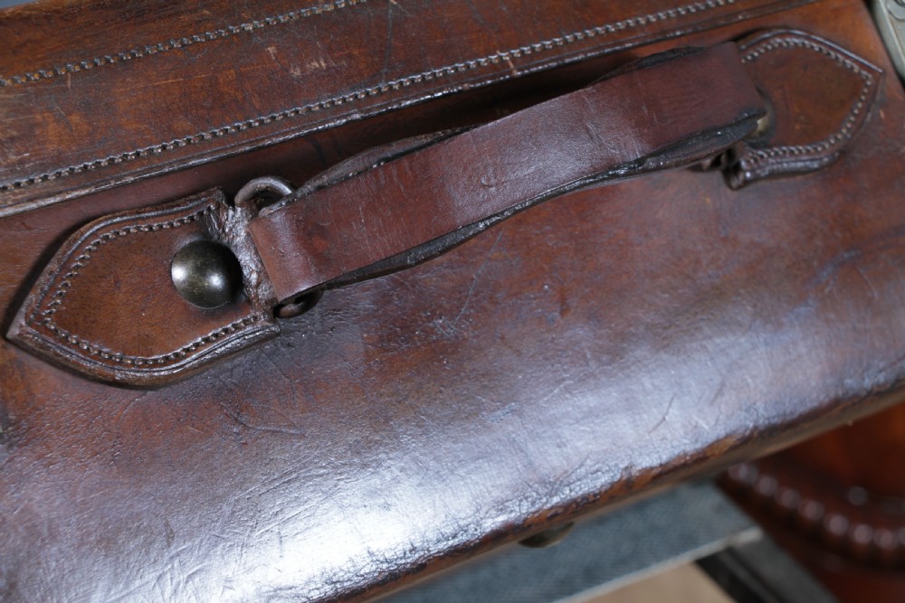 A rectangular chestnut brown leather suitcase with brass slide latches, a central leather handle, and black stencilled lettering reading C. ANTROBUS. View XI