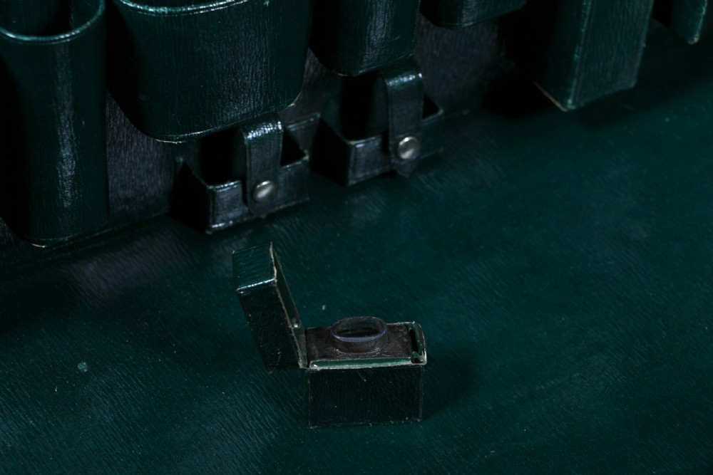 A rectangular chestnut brown leather suitcase with brass slide latches, a central leather handle, and black stencilled lettering reading C. ANTROBUS. View XXII