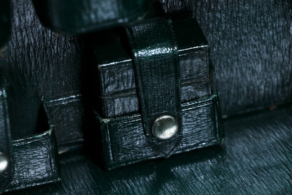 A rectangular chestnut brown leather suitcase with brass slide latches, a central leather handle, and black stencilled lettering reading C. ANTROBUS. View XXIV