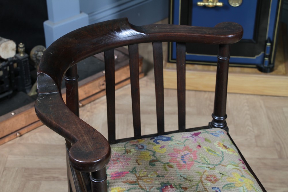 A dark elm Georgian corner chair with a curved top rail, slat back structure, turned supports, cross stretchers, and a floral tapestry drop-in seat. View IV