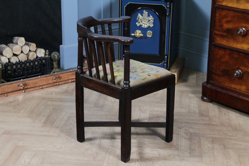 A dark elm Georgian corner chair with a curved top rail, slat back structure, turned supports, cross stretchers, and a floral tapestry drop-in seat. View VIII