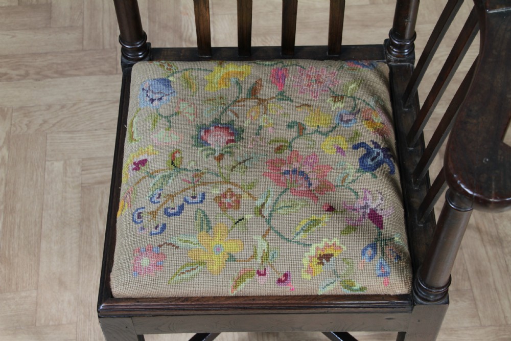 A dark elm Georgian corner chair with a curved top rail, slat back structure, turned supports, cross stretchers, and a floral tapestry drop-in seat. View IX