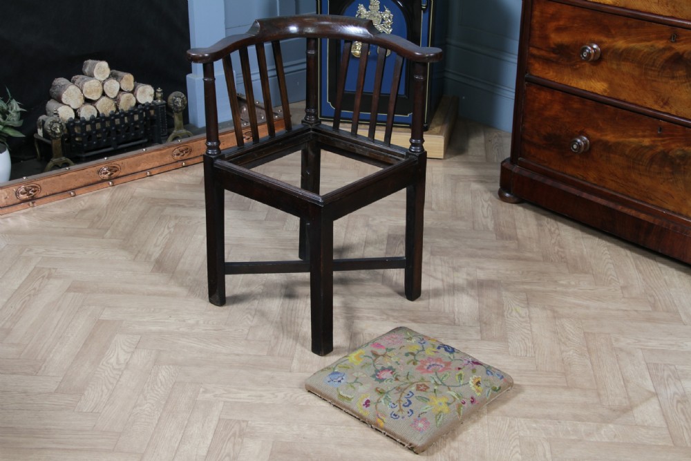 A dark elm Georgian corner chair with a curved top rail, slat back structure, turned supports, cross stretchers, and a floral tapestry drop-in seat. View X