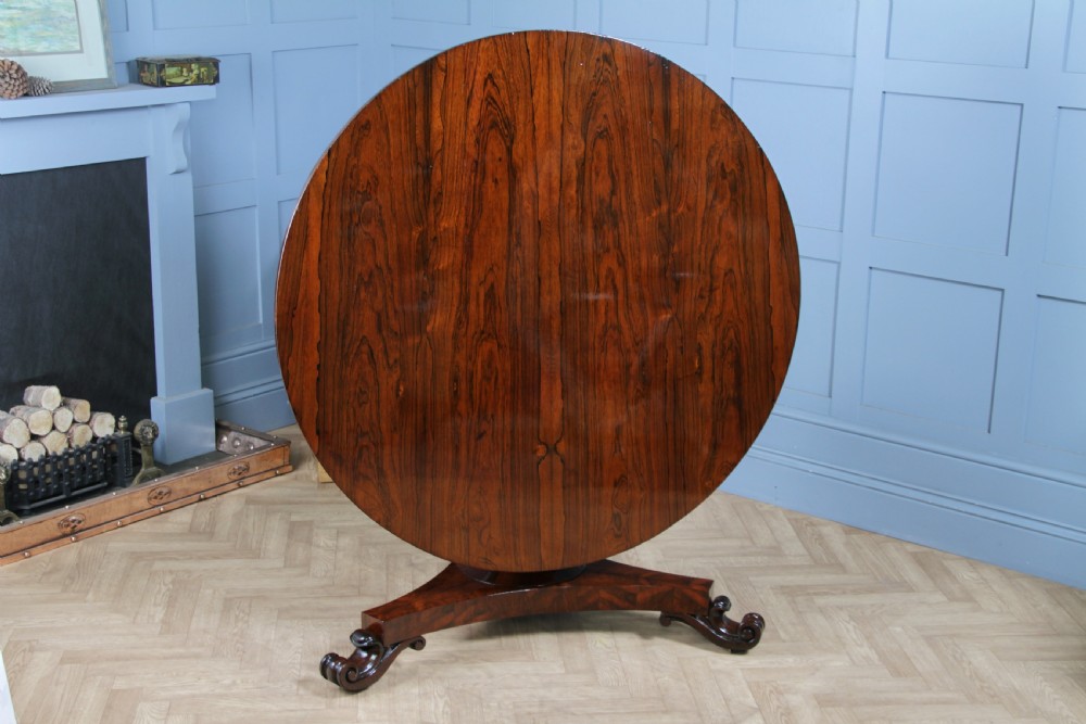 A circular dark rosewood centre table featuring a polished surface, a central bulbous faceted pedestal, and a triform base resting on carved scroll feet. View III