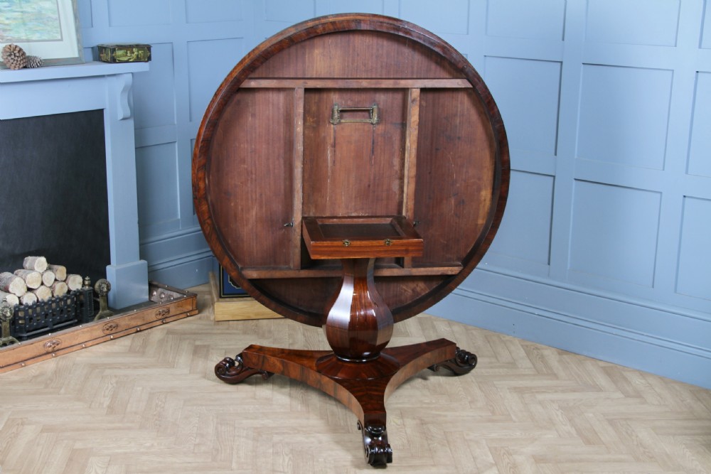 A circular dark rosewood centre table featuring a polished surface, a central bulbous faceted pedestal, and a triform base resting on carved scroll feet. View V