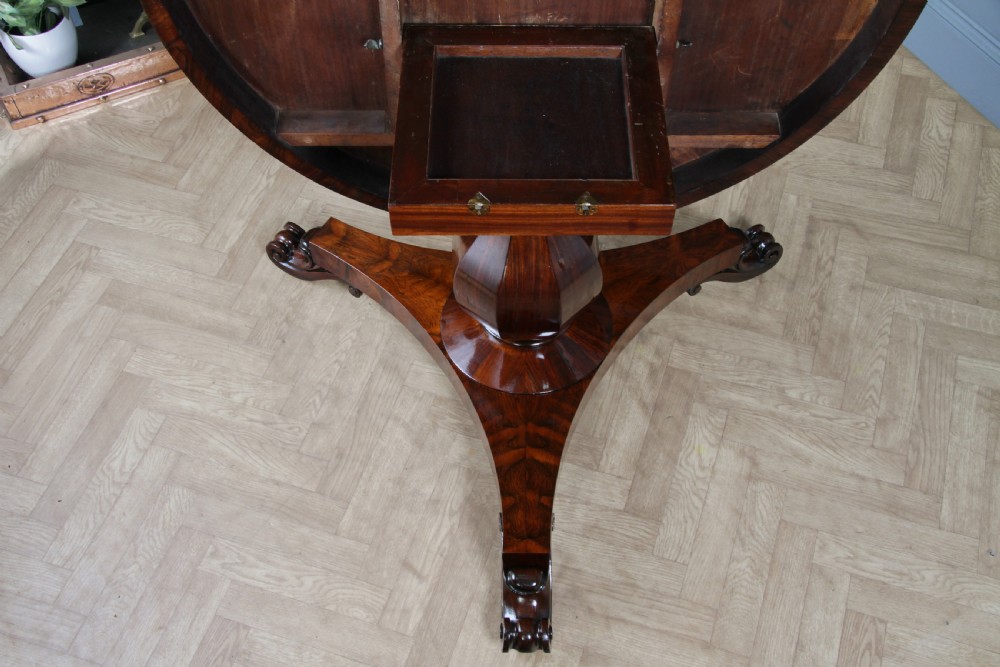 A circular dark rosewood centre table featuring a polished surface, a central bulbous faceted pedestal, and a triform base resting on carved scroll feet. View IX