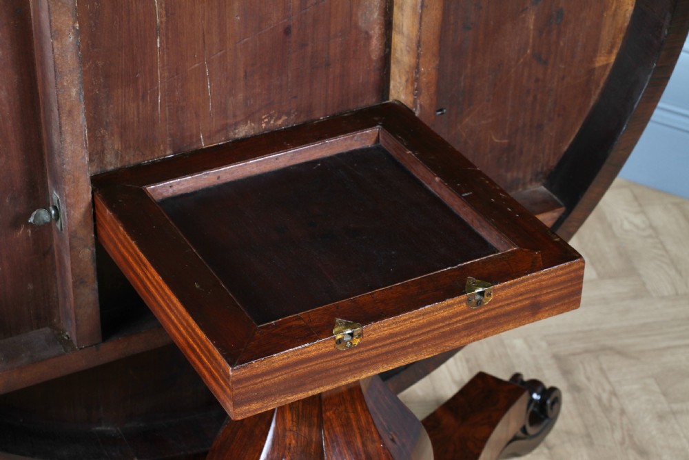 A circular dark rosewood centre table featuring a polished surface, a central bulbous faceted pedestal, and a triform base resting on carved scroll feet. View XI