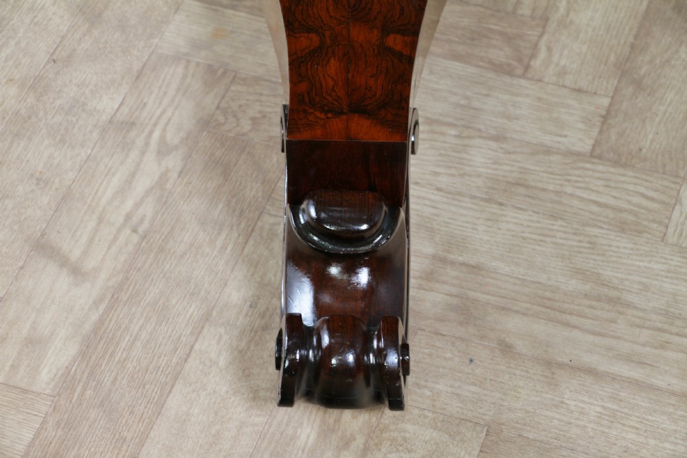 A circular dark rosewood centre table featuring a polished surface, a central bulbous faceted pedestal, and a triform base resting on carved scroll feet. View XIV