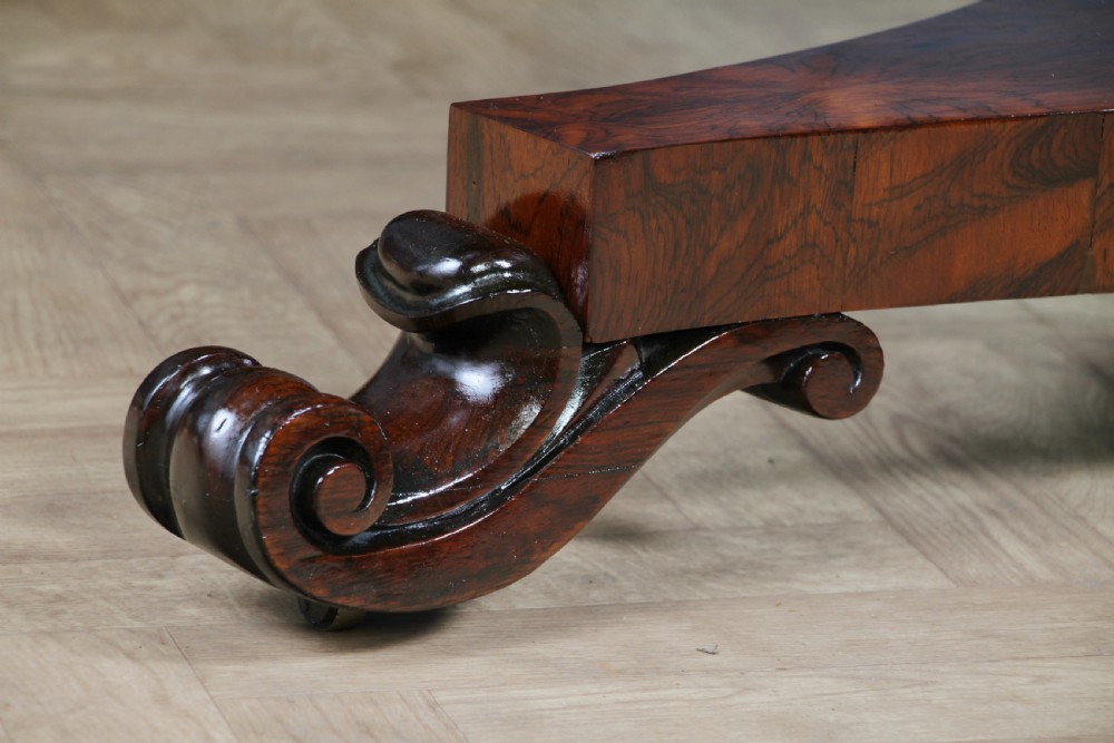 A circular dark rosewood centre table featuring a polished surface, a central bulbous faceted pedestal, and a triform base resting on carved scroll feet. View XVI