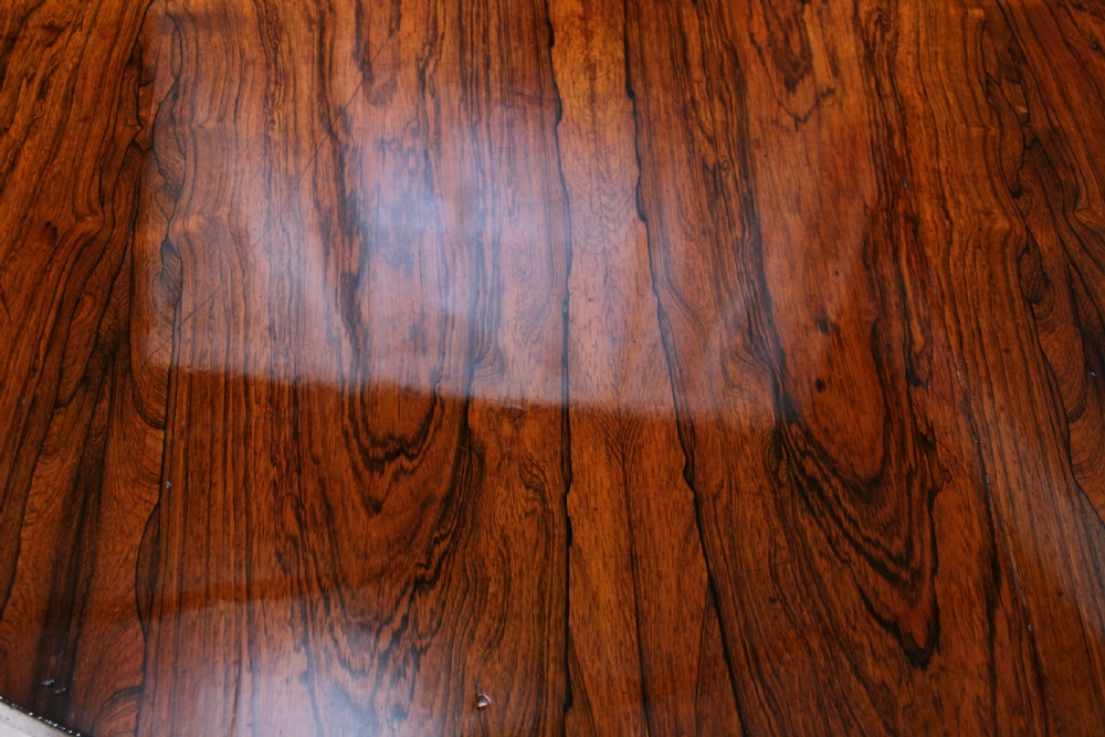 A circular dark rosewood centre table featuring a polished surface, a central bulbous faceted pedestal, and a triform base resting on carved scroll feet. View XXIII