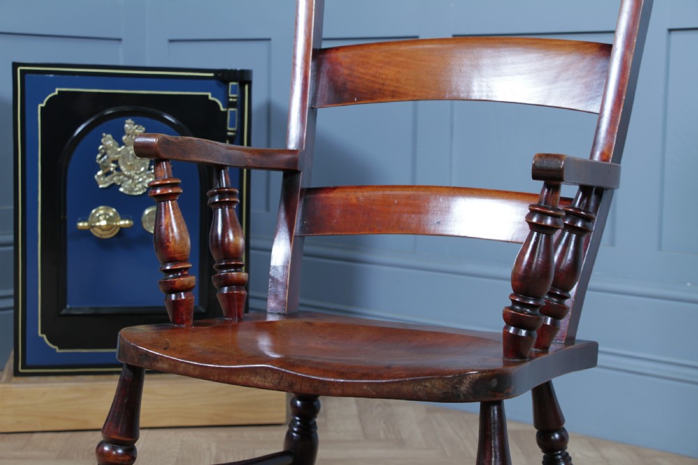 An antique Victorian ladder-back wooden rocking chair with three horizontal back slats, turned spindle arm supports, and curved rockers. View VII