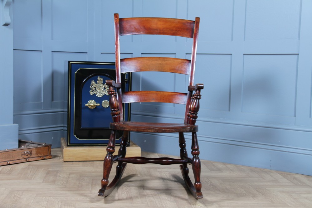 An antique Victorian ladder-back wooden rocking chair with three horizontal back slats, turned spindle arm supports, and curved rockers. View XIII