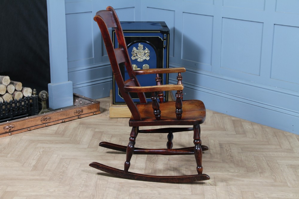 An antique Victorian ladder-back wooden rocking chair with three horizontal back slats, turned spindle arm supports, and curved rockers. View XV
