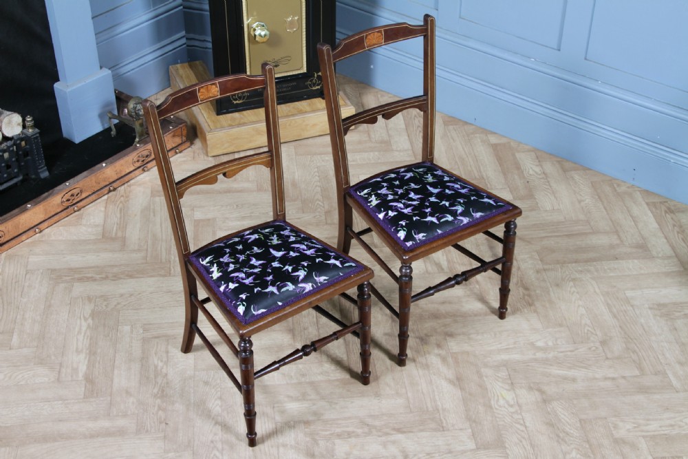 A pair of antique Edwardian mahogany side chairs featuring inlaid shell cresting, slender horizontal splats, turned legs, and dark silk patterned seats. View III