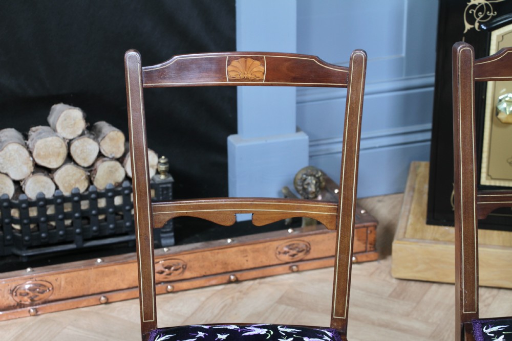 A pair of antique Edwardian mahogany side chairs featuring inlaid shell cresting, slender horizontal splats, turned legs, and dark silk patterned seats. View VII