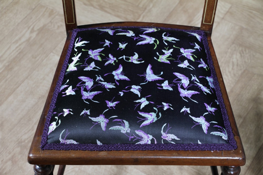 A pair of antique Edwardian mahogany side chairs featuring inlaid shell cresting, slender horizontal splats, turned legs, and dark silk patterned seats. View VIII