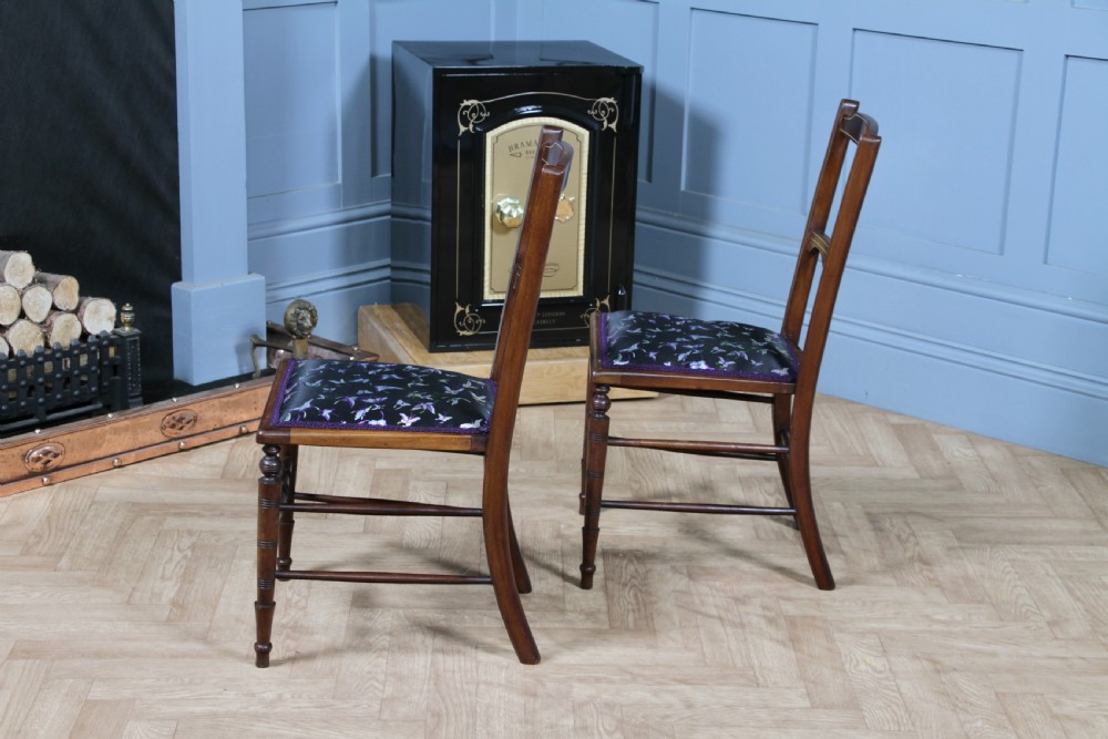 A pair of antique Edwardian mahogany side chairs featuring inlaid shell cresting, slender horizontal splats, turned legs, and dark silk patterned seats. View IX
