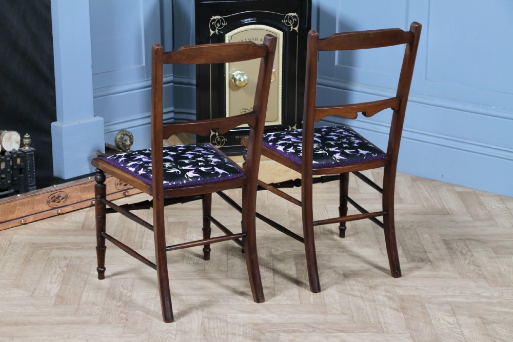 A pair of antique Edwardian mahogany side chairs featuring inlaid shell cresting, slender horizontal splats, turned legs, and dark silk patterned seats. View XI