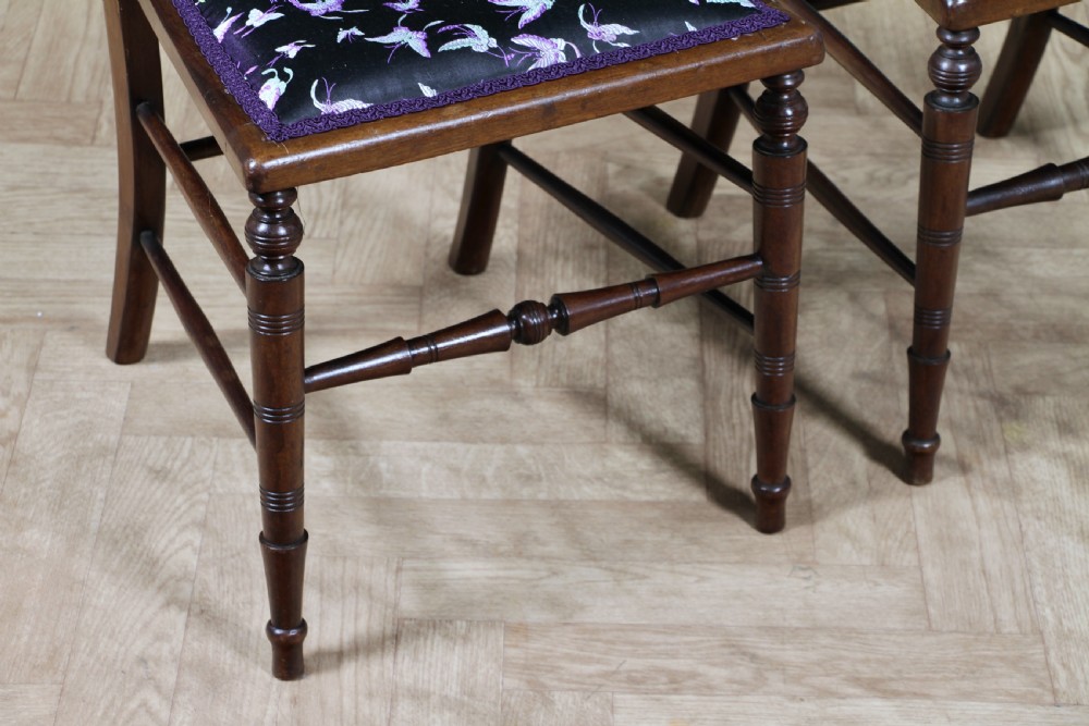 A pair of antique Edwardian mahogany side chairs featuring inlaid shell cresting, slender horizontal splats, turned legs, and dark silk patterned seats. View XII