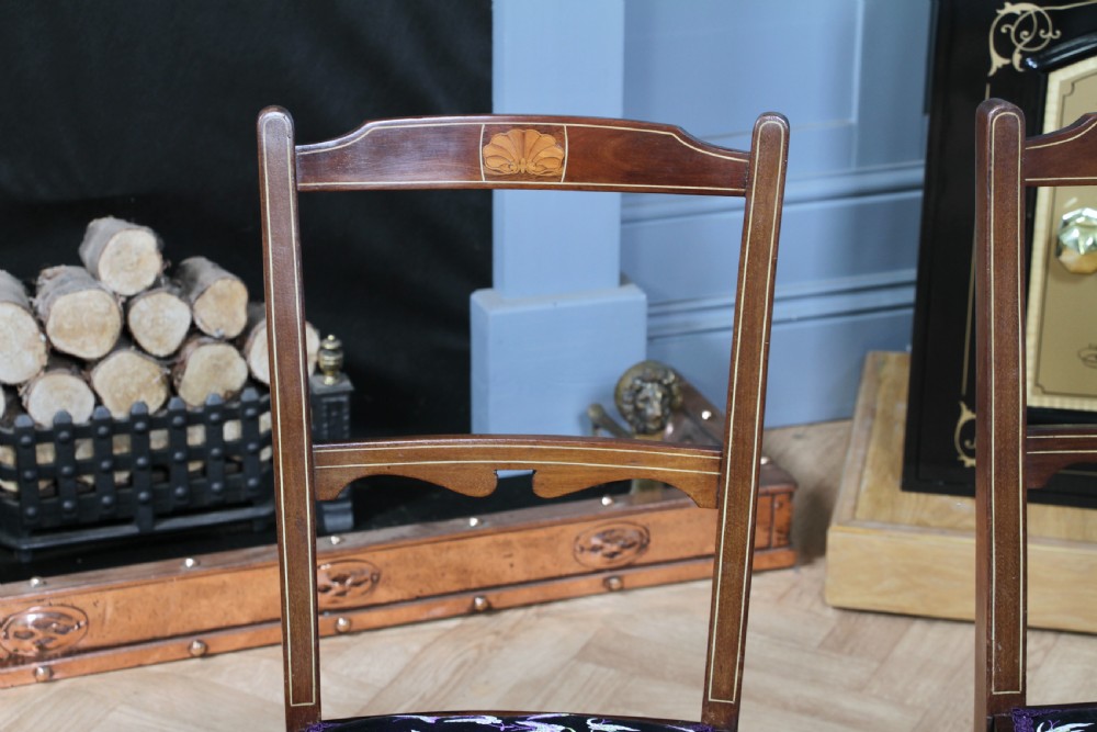A pair of antique Edwardian mahogany side chairs featuring inlaid shell cresting, slender horizontal splats, turned legs, and dark silk patterned seats. View XIII