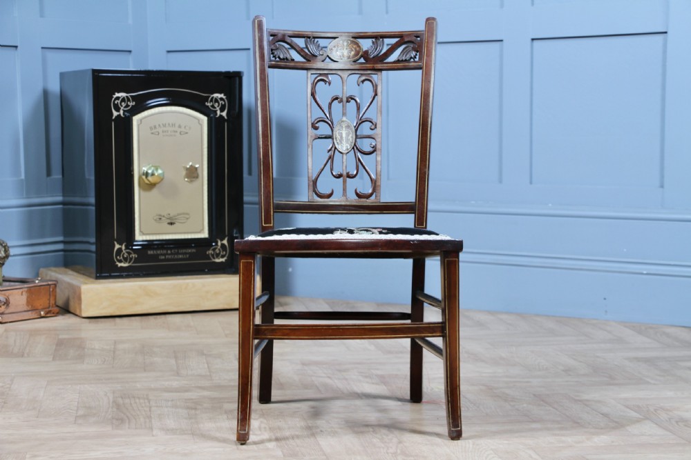 An Edwardian mahogany nursing chair featuring an inlaid pierced back splat, decorative stringing, and a black silk upholstered seat with embroidered floral motifs. View II
