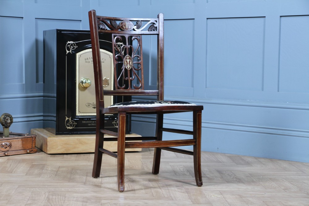 An Edwardian mahogany nursing chair featuring an inlaid pierced back splat, decorative stringing, and a black silk upholstered seat with embroidered floral motifs. View III