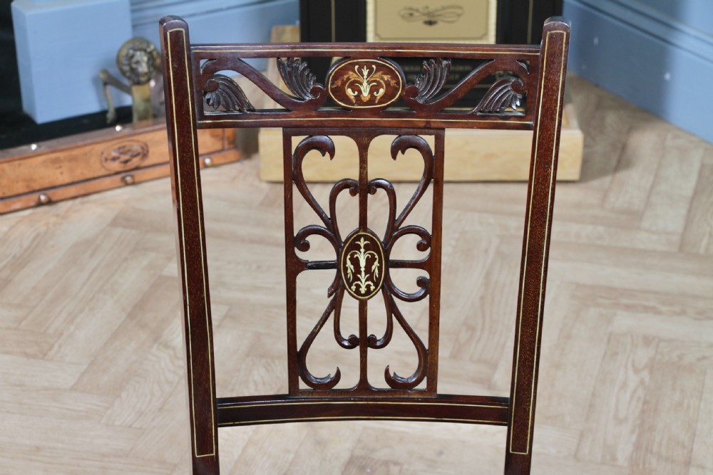 An Edwardian mahogany nursing chair featuring an inlaid pierced back splat, decorative stringing, and a black silk upholstered seat with embroidered floral motifs. View V