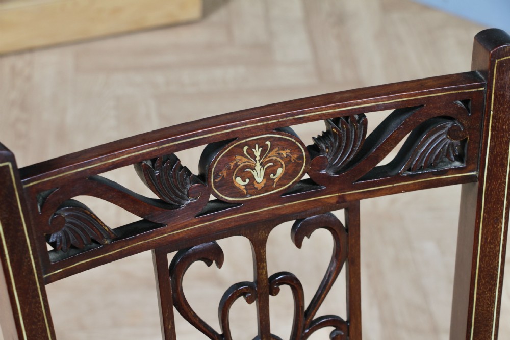An Edwardian mahogany nursing chair featuring an inlaid pierced back splat, decorative stringing, and a black silk upholstered seat with embroidered floral motifs. View VII
