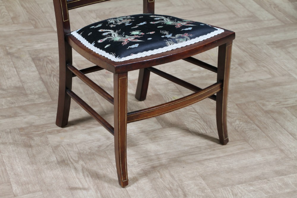 An Edwardian mahogany nursing chair featuring an inlaid pierced back splat, decorative stringing, and a black silk upholstered seat with embroidered floral motifs. View VIII