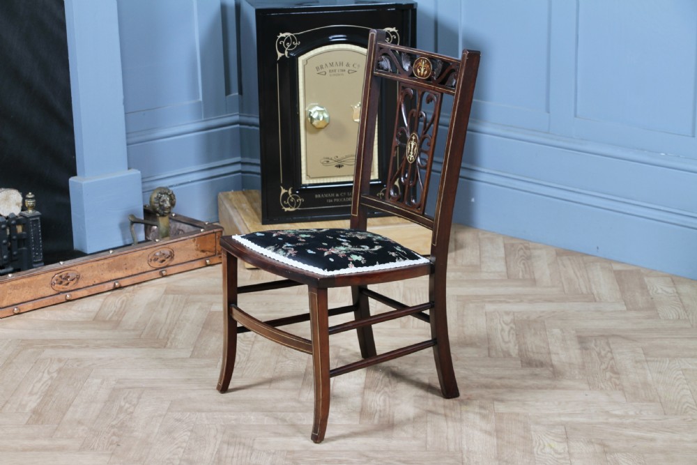 An Edwardian mahogany nursing chair featuring an inlaid pierced back splat, decorative stringing, and a black silk upholstered seat with embroidered floral motifs. View XI