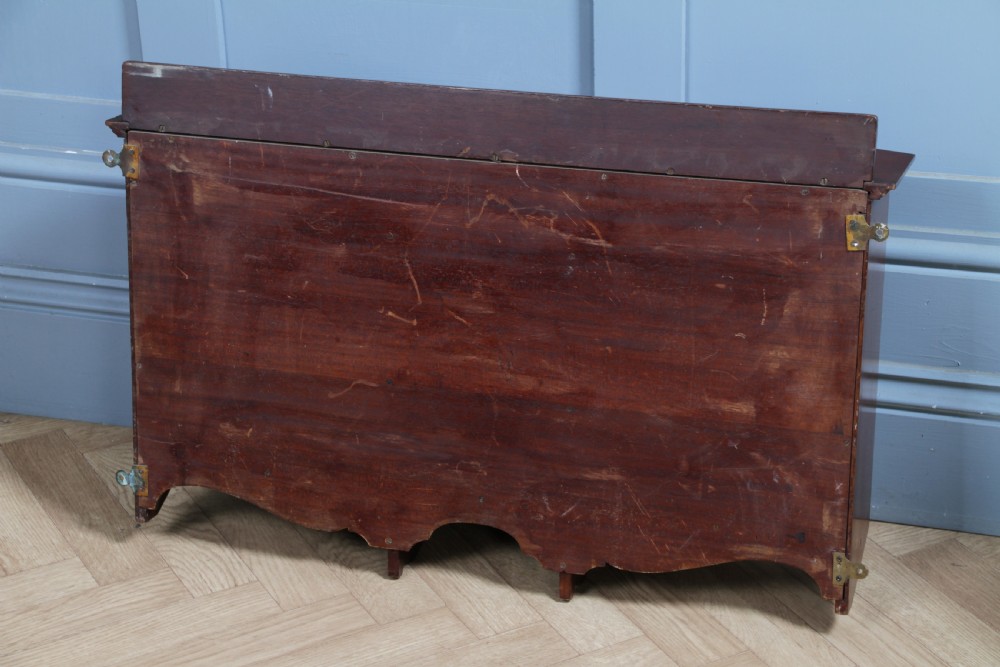 A small Edwardian mahogany wall hanging cabinet featuring two outer cupboards, three central drawers, brass handles, and a low back gallery. View XXIV