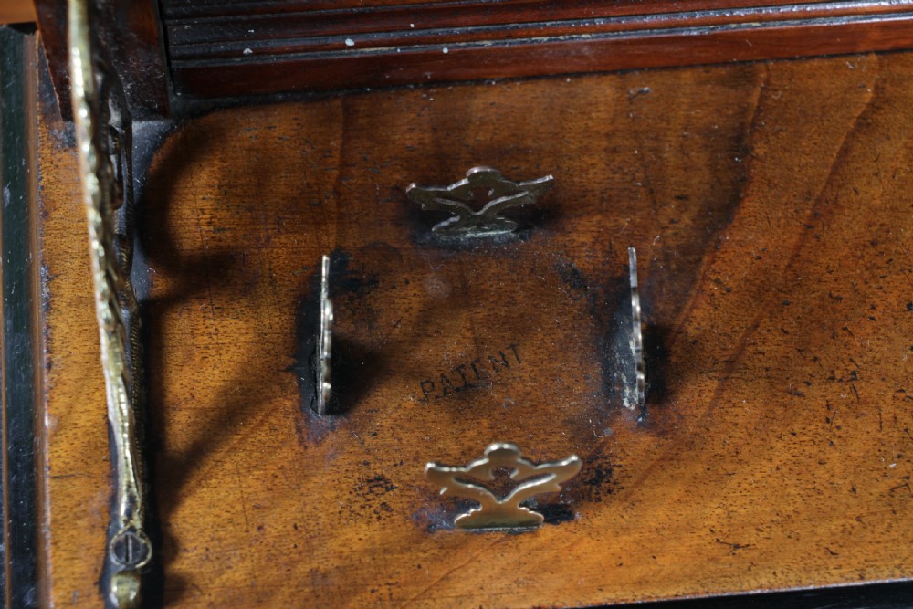 An Edwardian wooden inkstand featuring two glass inkwells, a shaped back gallery with finials, brass side supports, a pen groove, and a lower drawer. View XV