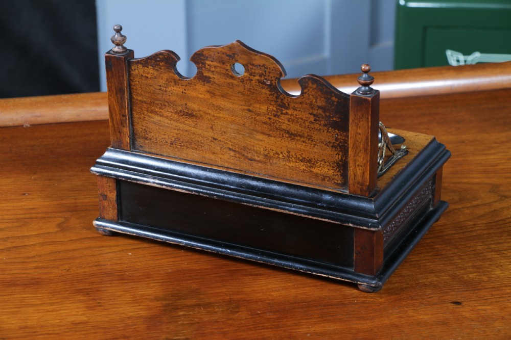 An Edwardian wooden inkstand featuring two glass inkwells, a shaped back gallery with finials, brass side supports, a pen groove, and a lower drawer. View XX