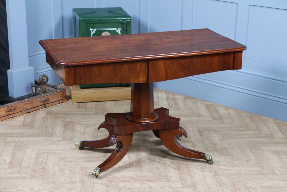 A Regency period mahogany centre table featuring a rectangular top with rounded corners on a central octagonal column and quadform platform base with swept legs.
