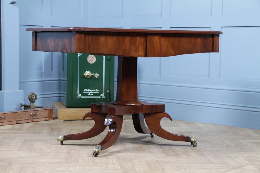 A Regency period mahogany centre table featuring a rectangular top with rounded corners on a central octagonal column and quadform platform base with swept legs. View III