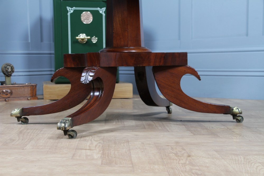 A Regency period mahogany centre table featuring a rectangular top with rounded corners on a central octagonal column and quadform platform base with swept legs. View VI