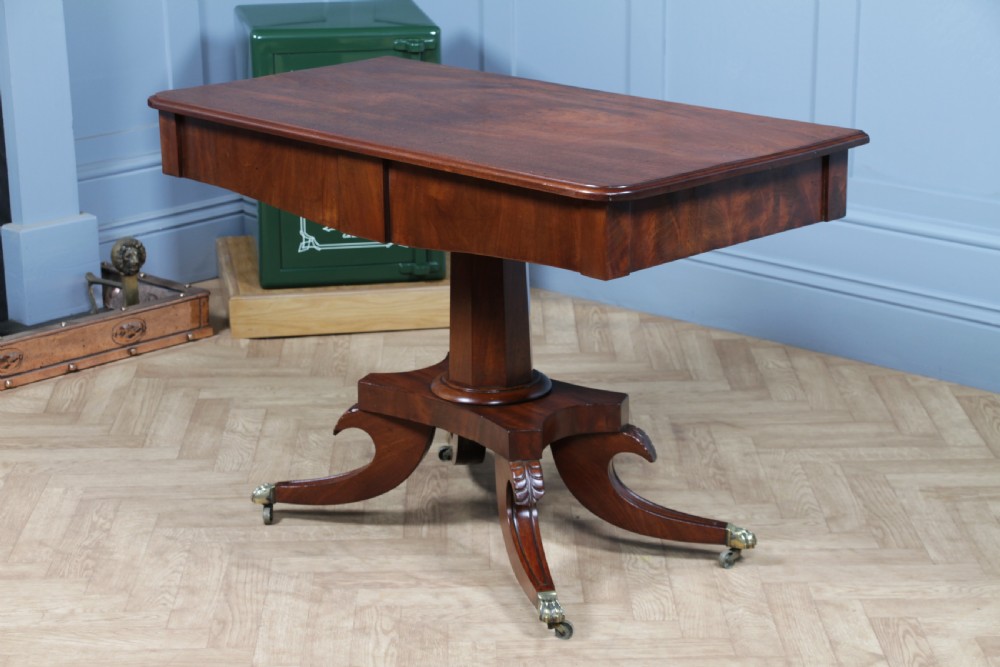 A Regency period mahogany centre table featuring a rectangular top with rounded corners on a central octagonal column and quadform platform base with swept legs. View XIX