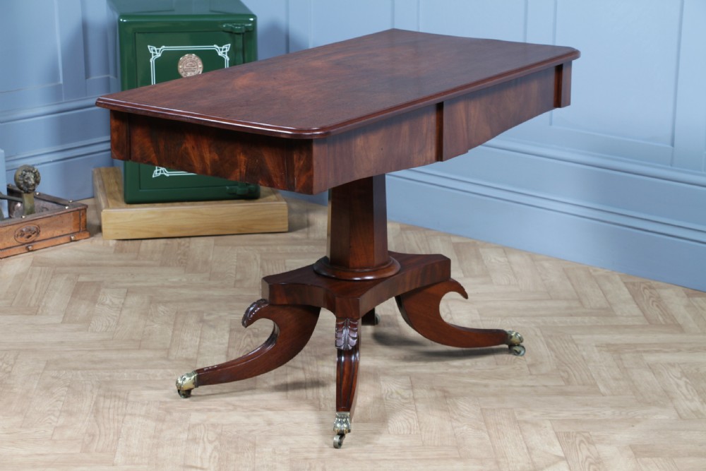 A Regency period mahogany centre table featuring a rectangular top with rounded corners on a central octagonal column and quadform platform base with swept legs. View XX