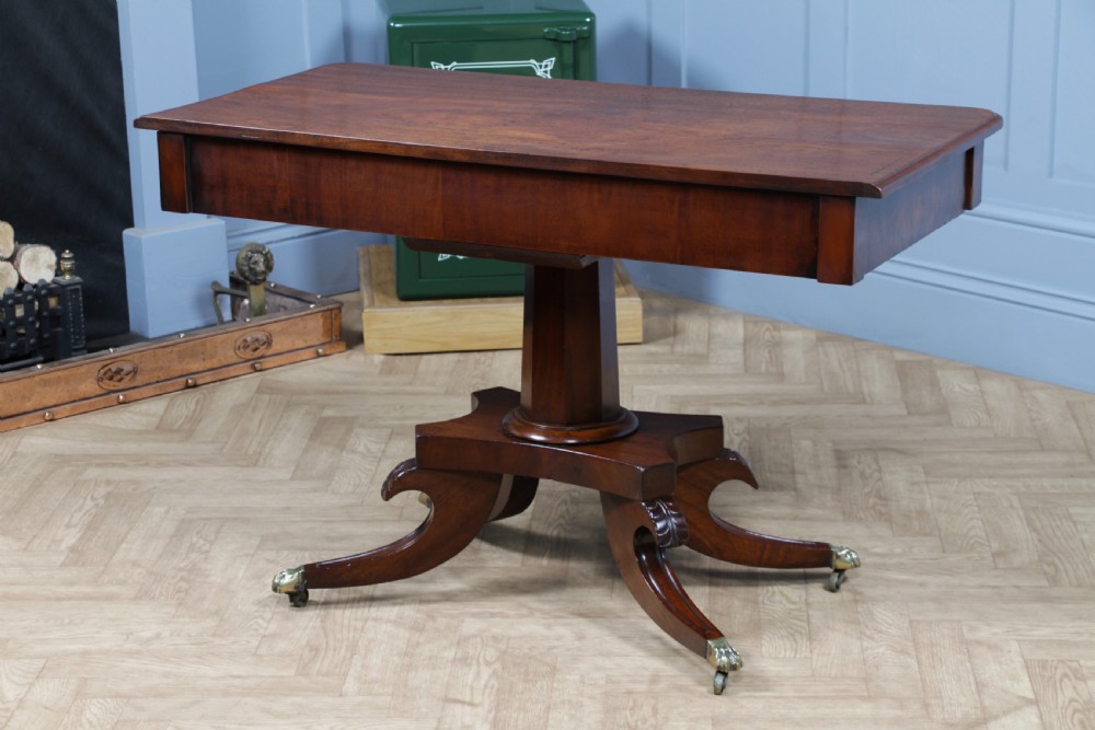 A Regency period mahogany centre table featuring a rectangular top with rounded corners on a central octagonal column and quadform platform base with swept legs. View XXI