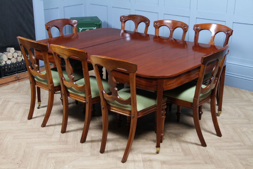 An extended Georgian mahogany dining table featuring semi-circular D-ends, a central drop-leaf section, square tapered legs, and brass castors. View V