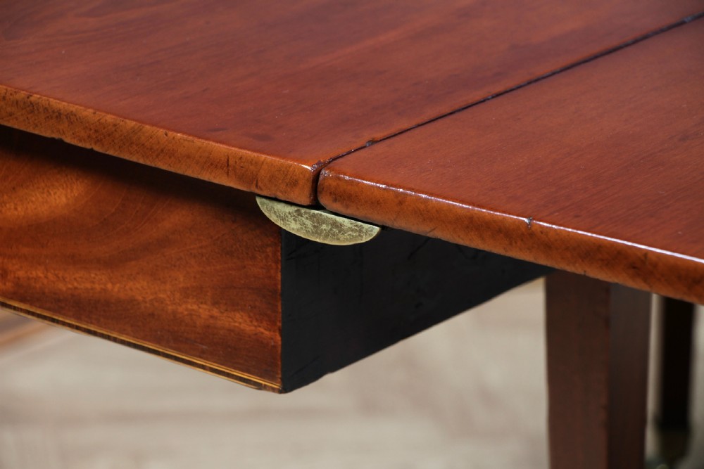 An extended Georgian mahogany dining table featuring semi-circular D-ends, a central drop-leaf section, square tapered legs, and brass castors. View X