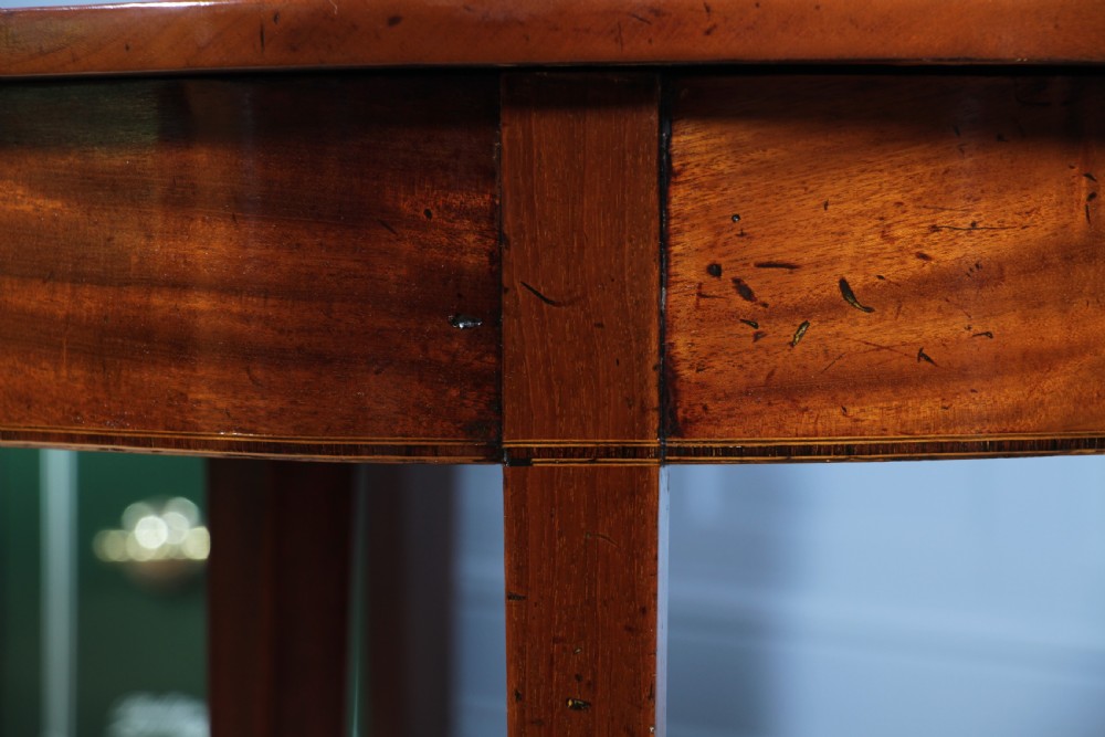 An extended Georgian mahogany dining table featuring semi-circular D-ends, a central drop-leaf section, square tapered legs, and brass castors. View XII