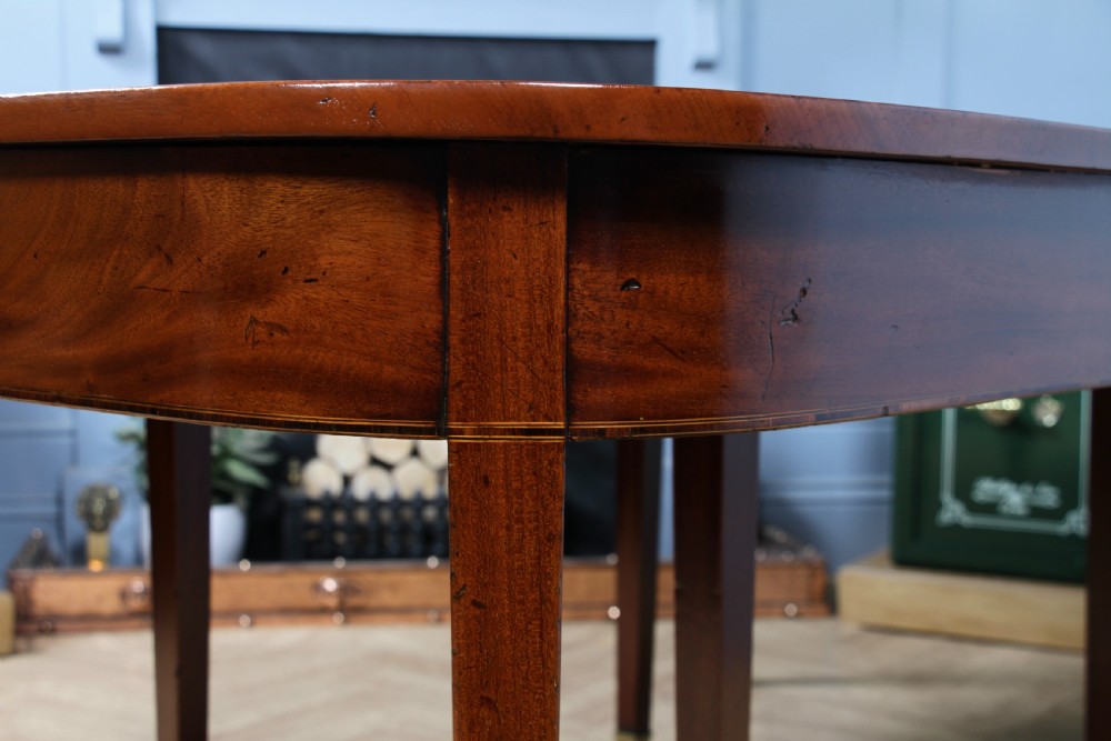 An extended Georgian mahogany dining table featuring semi-circular D-ends, a central drop-leaf section, square tapered legs, and brass castors. View XIII