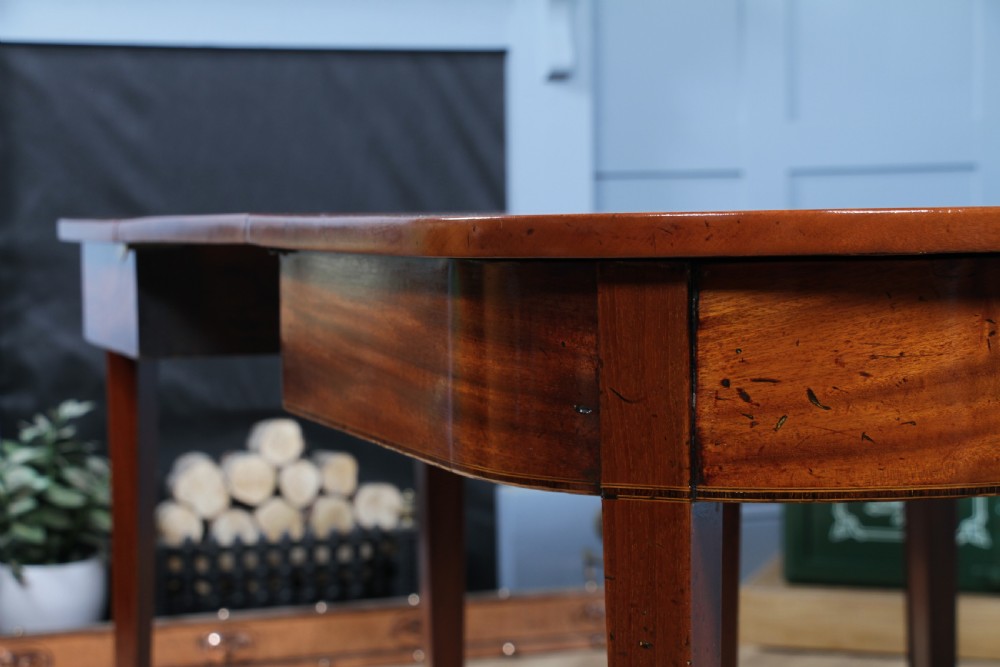 An extended Georgian mahogany dining table featuring semi-circular D-ends, a central drop-leaf section, square tapered legs, and brass castors. View XIV