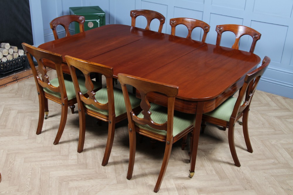 An extended Georgian mahogany dining table featuring semi-circular D-ends, a central drop-leaf section, square tapered legs, and brass castors. View XXIV