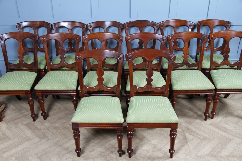 A set of fourteen Victorian mahogany dining chairs featuring carved crown splats, turned front legs, and green patterned upholstered seats. View III