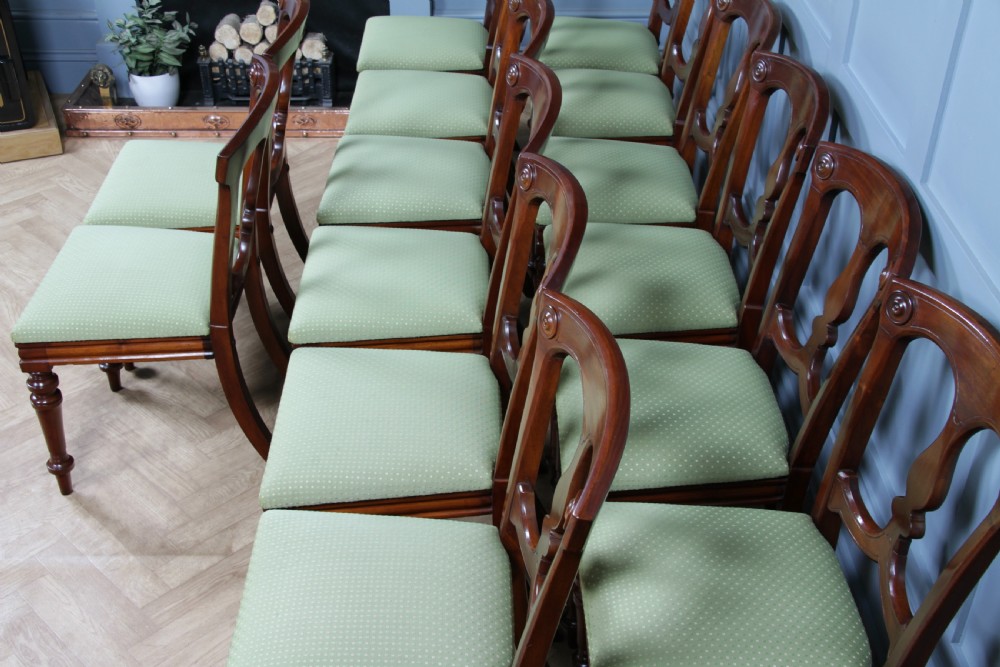A set of fourteen Victorian mahogany dining chairs featuring carved crown splats, turned front legs, and green patterned upholstered seats. View IV